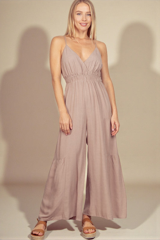 Woman wearing a mauve jumpsuit against a plain background