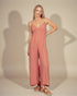 Woman wearing a pink jumpsuit against a neutral background