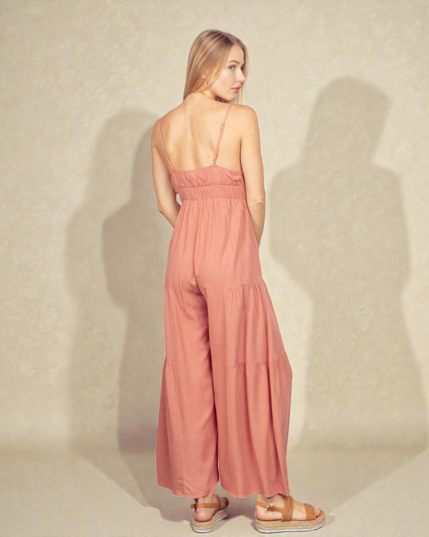 Woman wearing a pink jumpsuit against a plain background