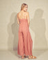 Woman wearing a pink jumpsuit against a plain background