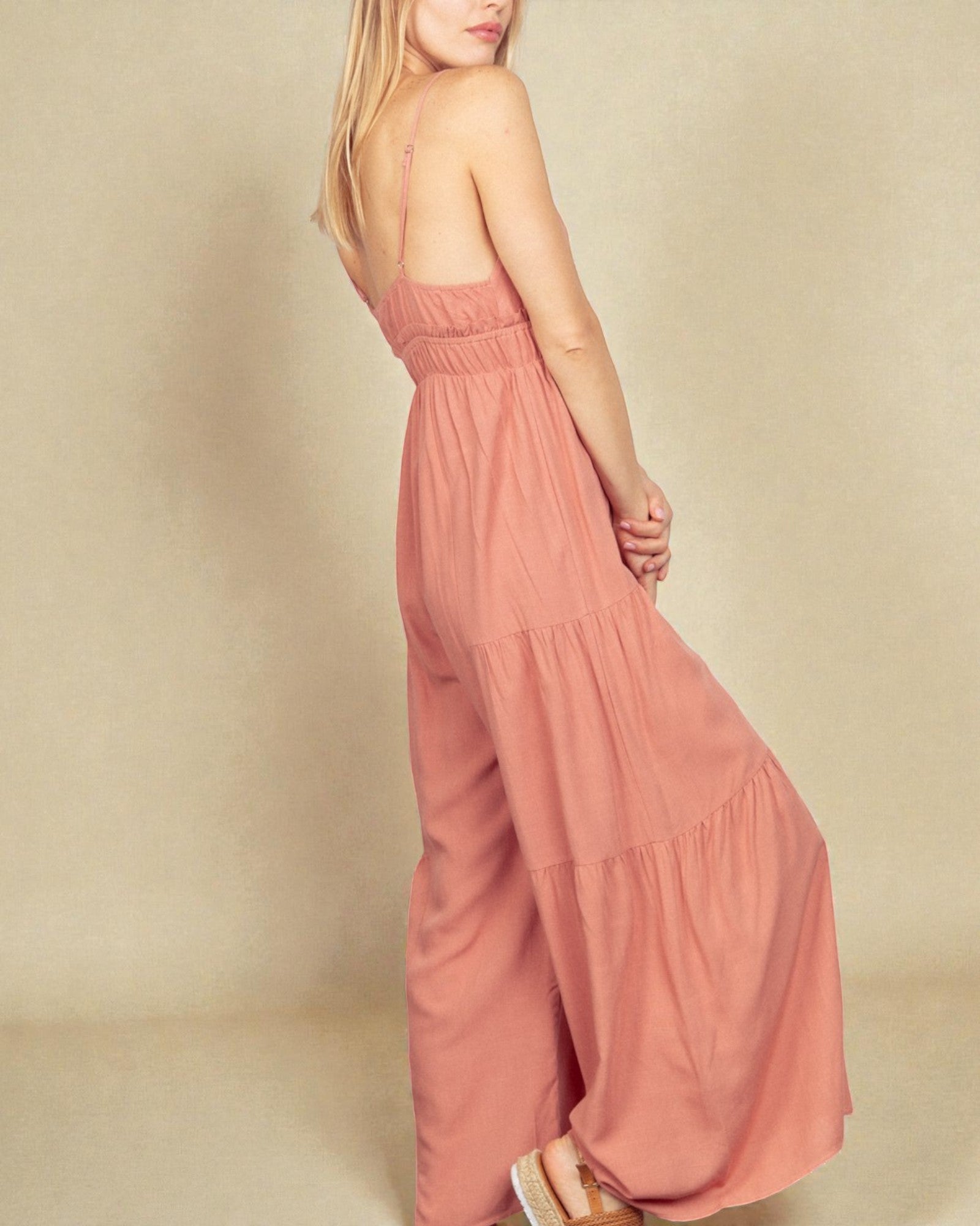 Woman wearing a pink jumpsuit on a beige background