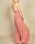 Woman wearing a pink jumpsuit on a beige background