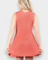 Woman wearing a coral knitted dress against a plain background