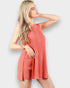 Woman wearing a coral ribbed romper against a light gray background