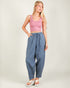 Woman wearing a pink crop top and blue high-waisted pants on a white background