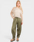 Woman wearing a beige knit sweater and olive green pants on a white background