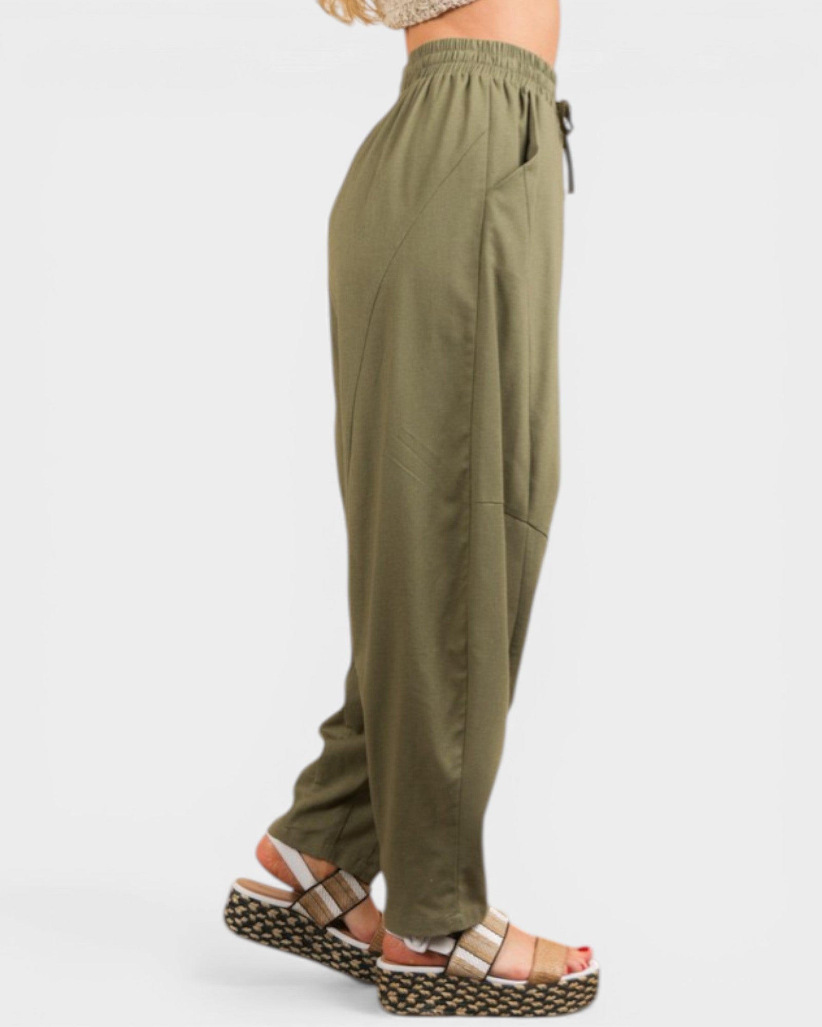 Olive green pants worn by a person on a white background