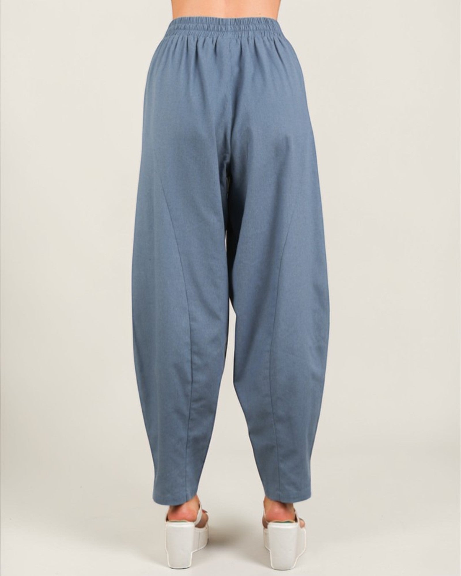 Blue baggy pants worn by a person on a white background