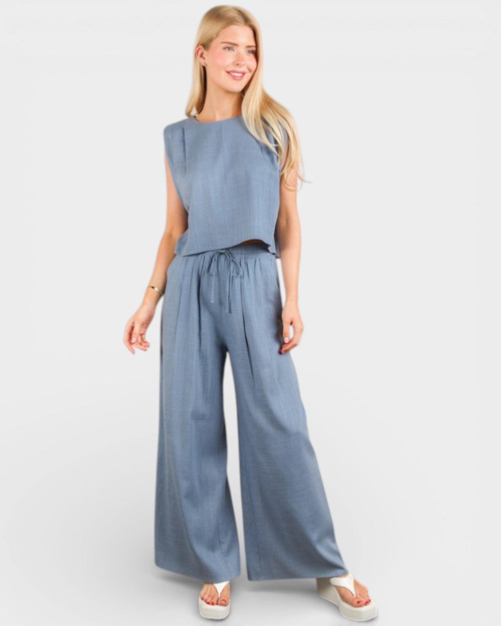 Woman wearing a blue jumpsuit on a light gray background