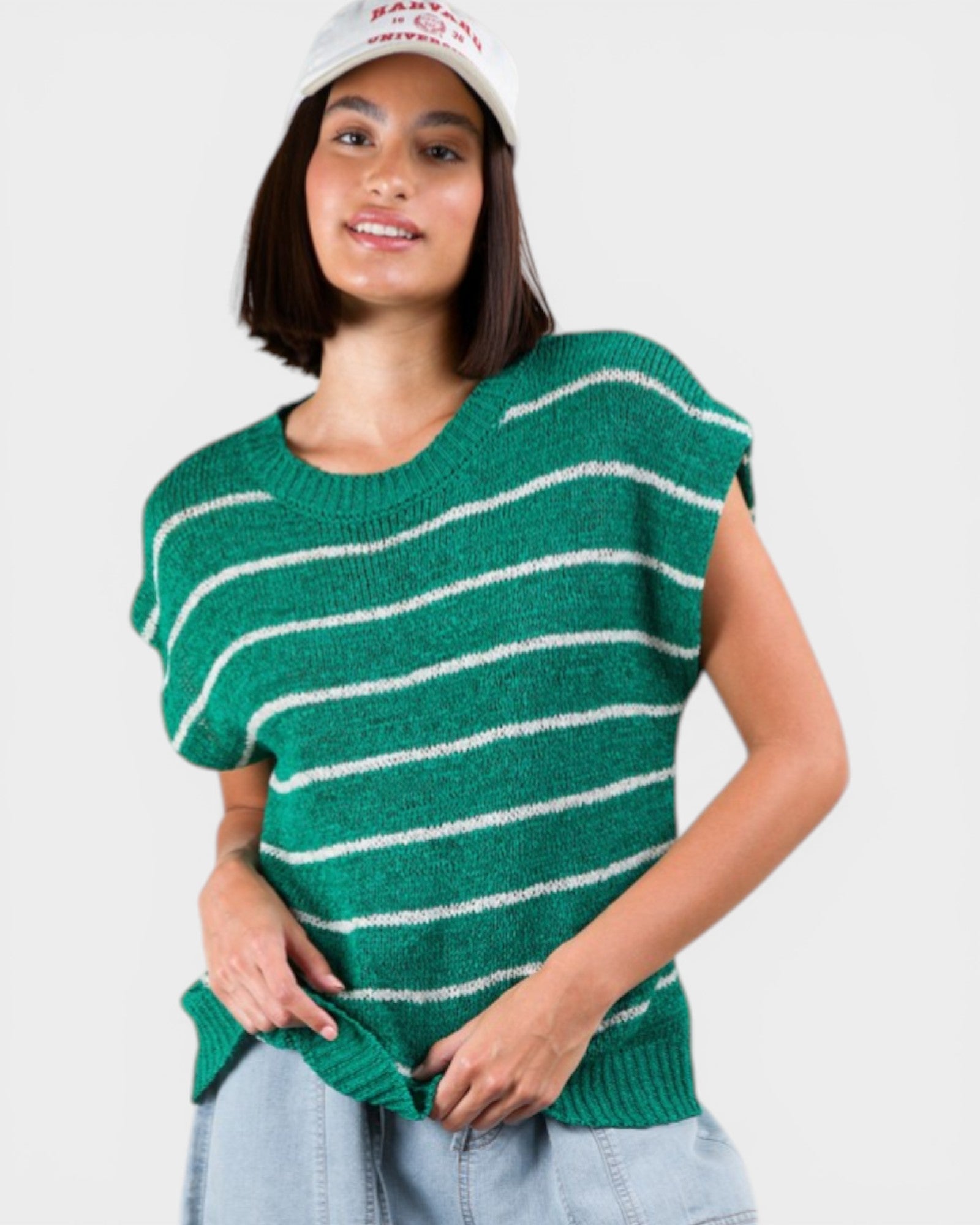 Woman wearing a green and white striped sweater vest on a plain background