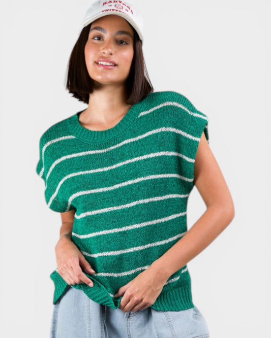 Woman wearing a green and white striped sweater vest on a plain background