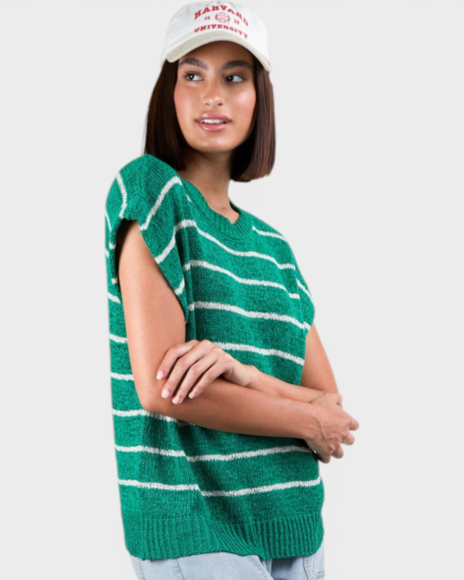 Woman wearing a green and white striped sweater vest on a plain background