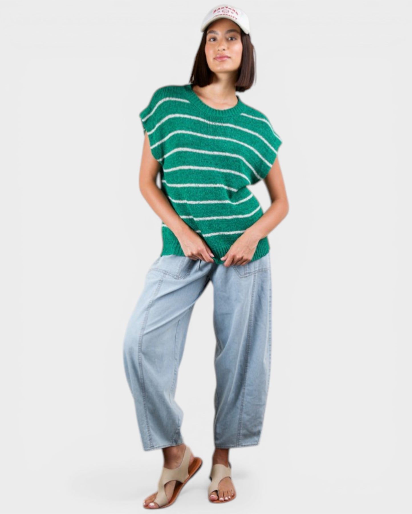 Woman wearing a green striped shirt and light blue pants on a white background