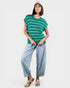 Woman wearing a green striped shirt and light blue pants on a white background