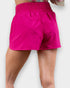 Bright pink shorts worn by a person on a white background