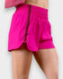Bright pink shorts worn by a person on a light gray background