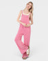 Woman wearing a pink corduroy jumpsuit on a white background