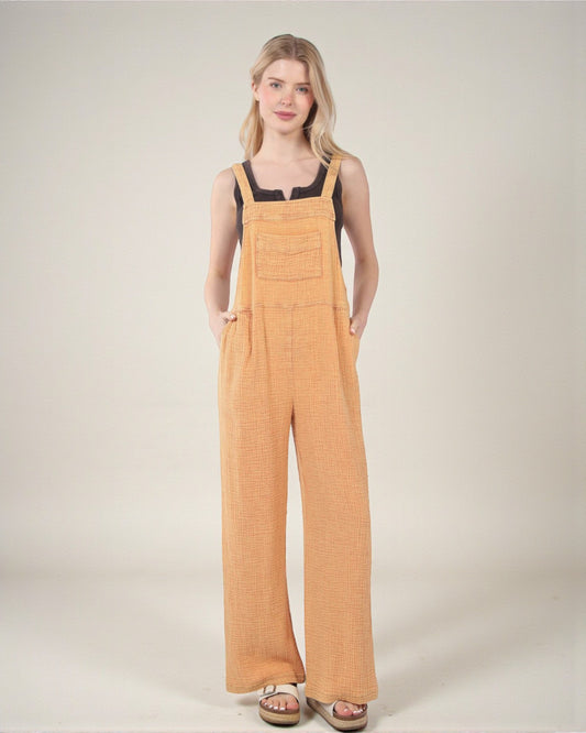Woman wearing mustard yellow overalls on a plain background