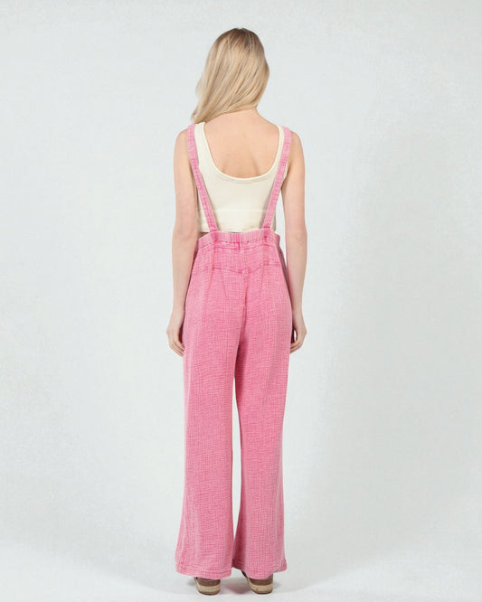 Person wearing pink checkered overalls on a white background