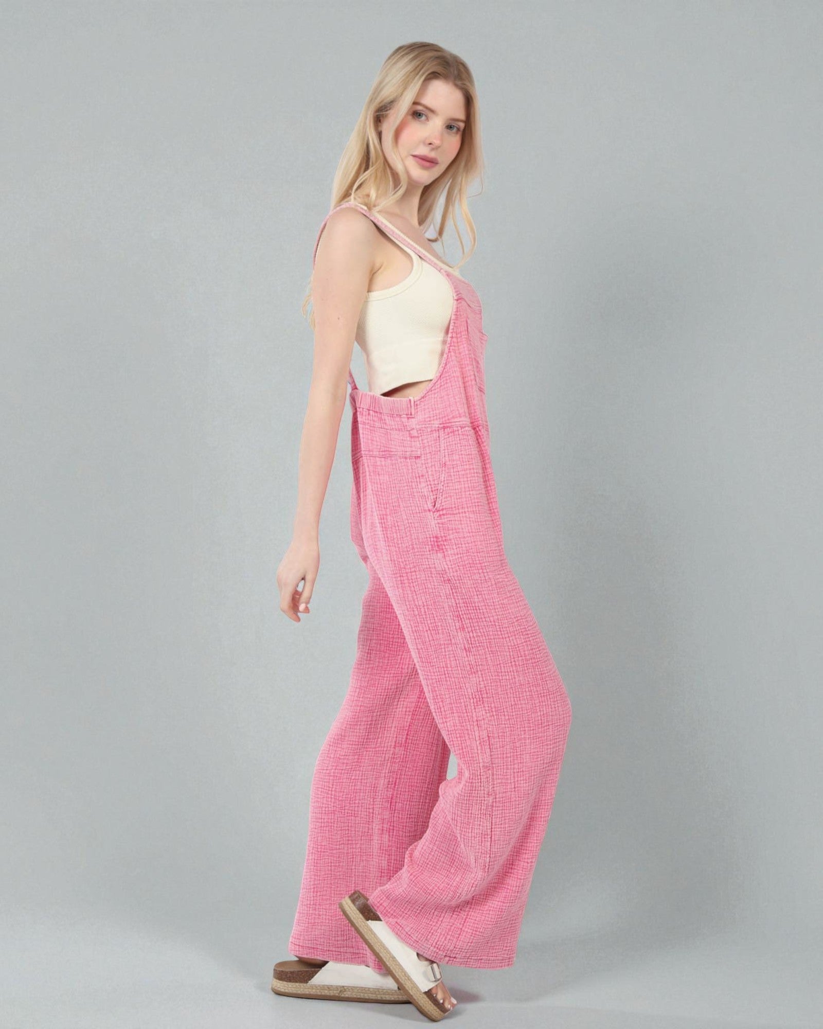 Woman wearing a pink corduroy jumpsuit on a gray background