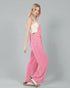Woman wearing a pink corduroy jumpsuit on a gray background