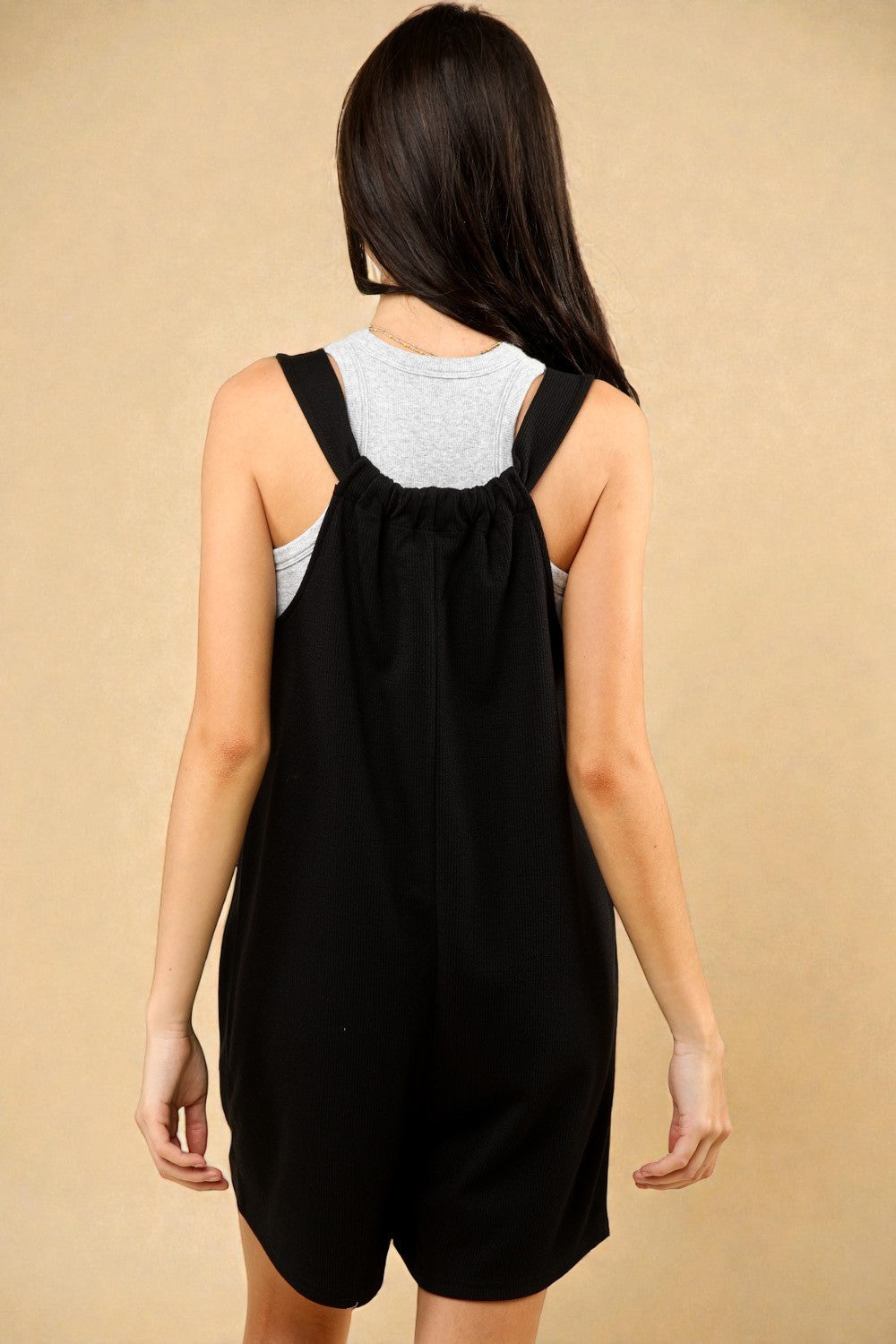 Person wearing a black dress with a beige background