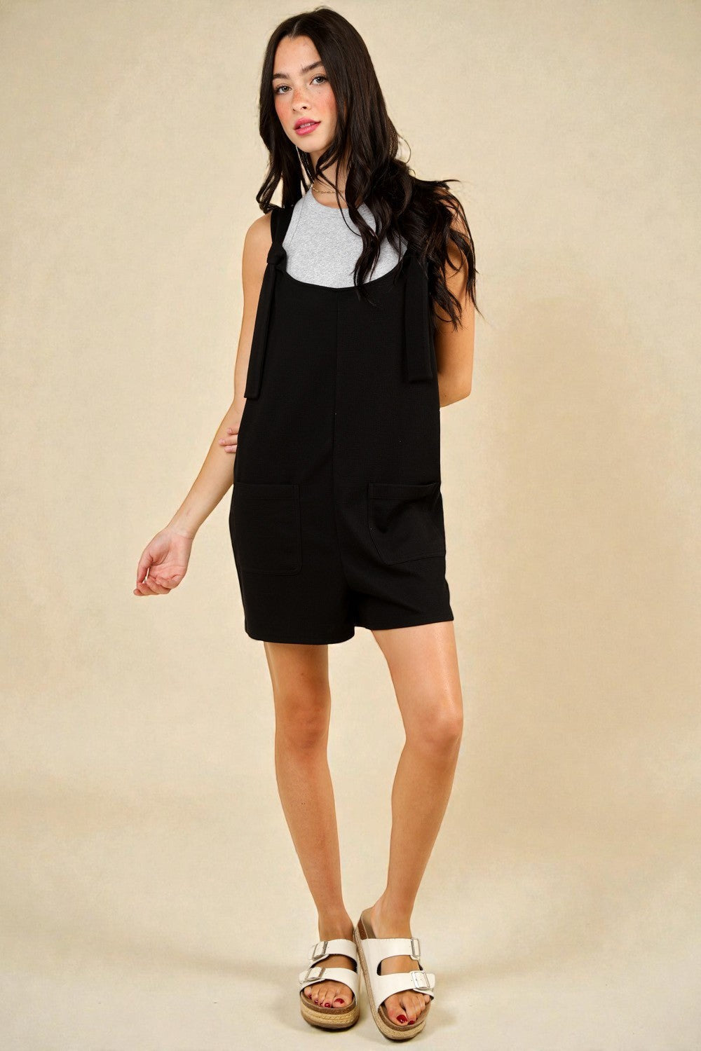 Woman wearing a black dress over a white shirt on a beige background