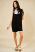 Woman wearing a black dress over a white shirt on a beige background