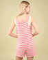 Woman wearing a pink and white striped romper against a beige background