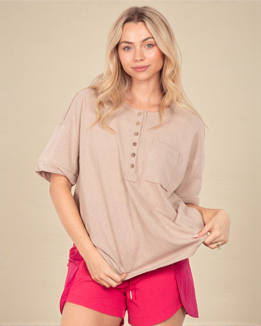 Woman wearing a beige short-sleeve top and pink shorts on a beige background