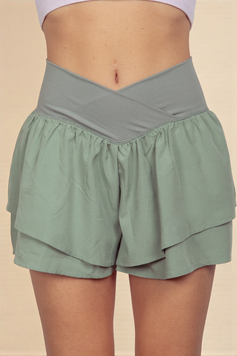 Green layered shorts worn by a person on a beige background