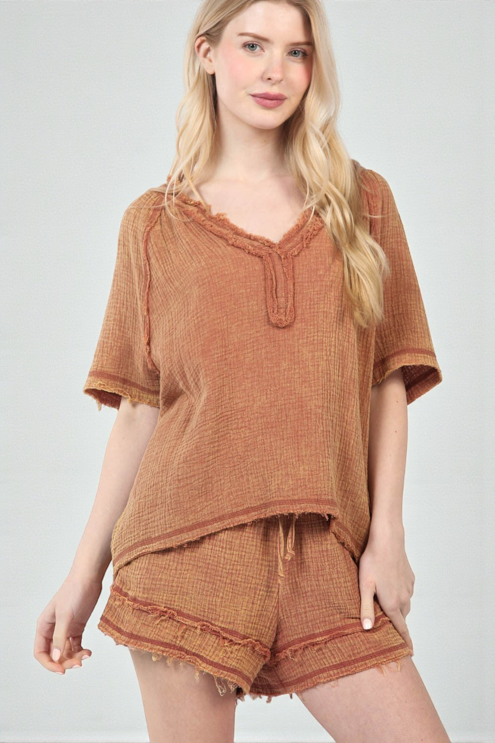 Woman wearing a rust-colored top and shorts set on a white background