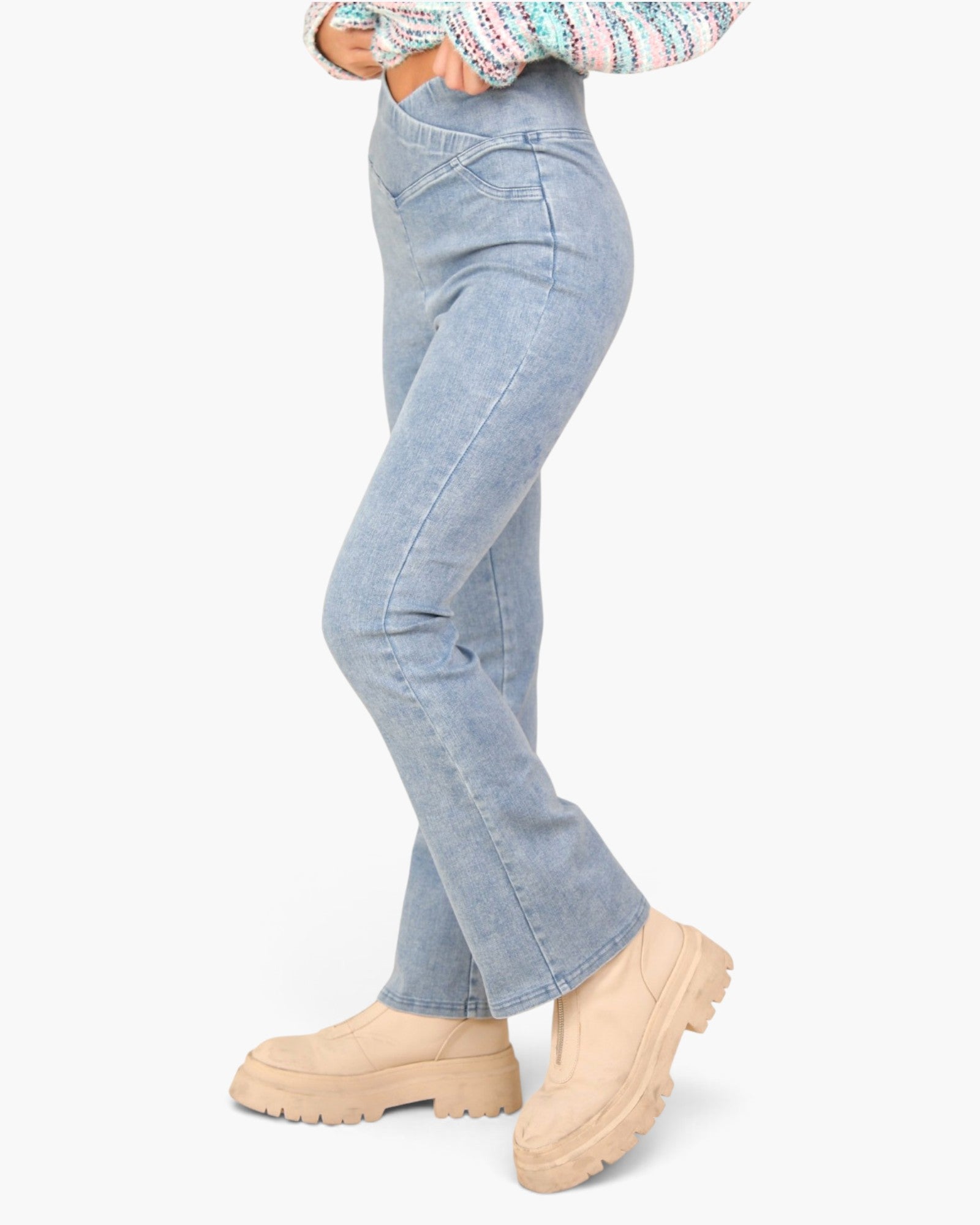 A person wearing light-wash blue jeans and beige chunky platform boots, shown from the waist down against a plain light gray studio background.
