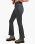 A person wearing dark gray flared denim jeans, olive green lace-up ankle boots, and a pink striped cropped sweater, shown from the waist down against a plain white background.