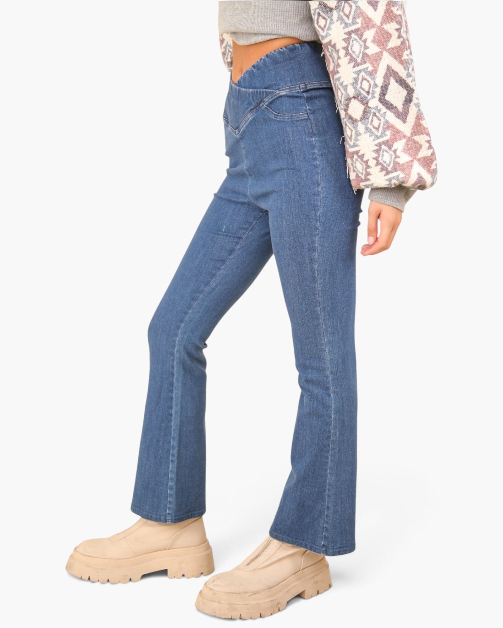 A model wearing blue high-waisted flare jeans, a gray top, and beige chunky platform boots, shown from the waist down against a light gray studio background.