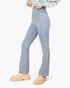 A model wearing light-wash blue high-rise flare jeans, paired with beige chunky platform boots and a multicolor knit top, shown from the waist down against a plain white background.