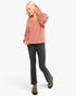 A woman modeling a dusty rose long-sleeve knit top with voluminous balloon sleeves, paired with dark gray jeans and olive green shoes, against a plain white studio background.