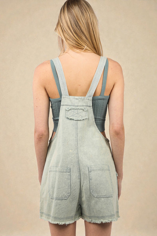 Light denim overalls worn by a person on a beige background