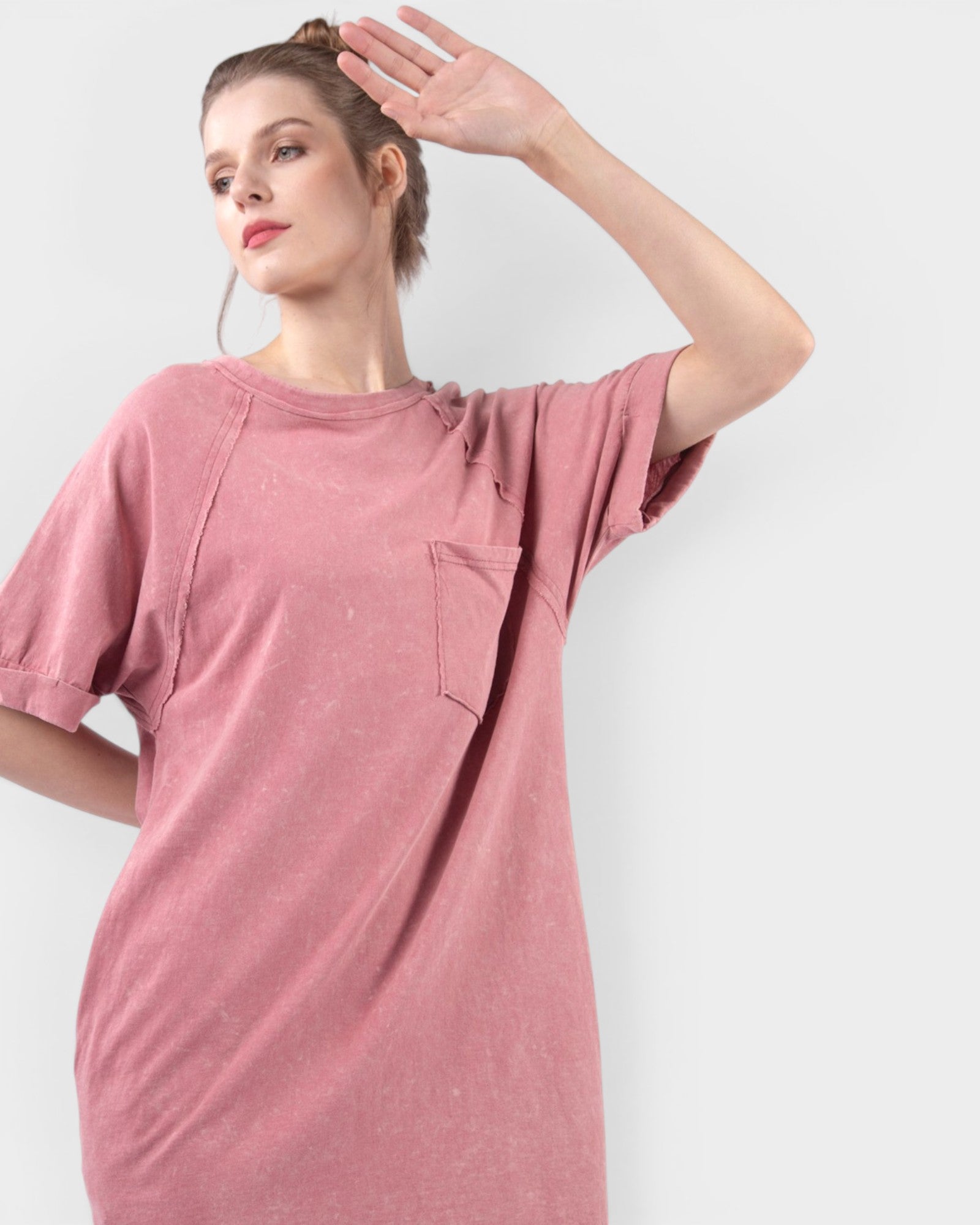 Woman wearing a pink t-shirt dress against a white background