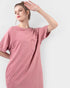 Woman wearing a pink t-shirt dress against a white background