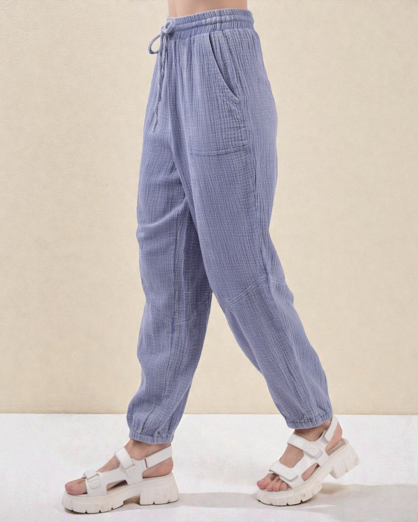Blue corduroy pants worn by a person on a beige background