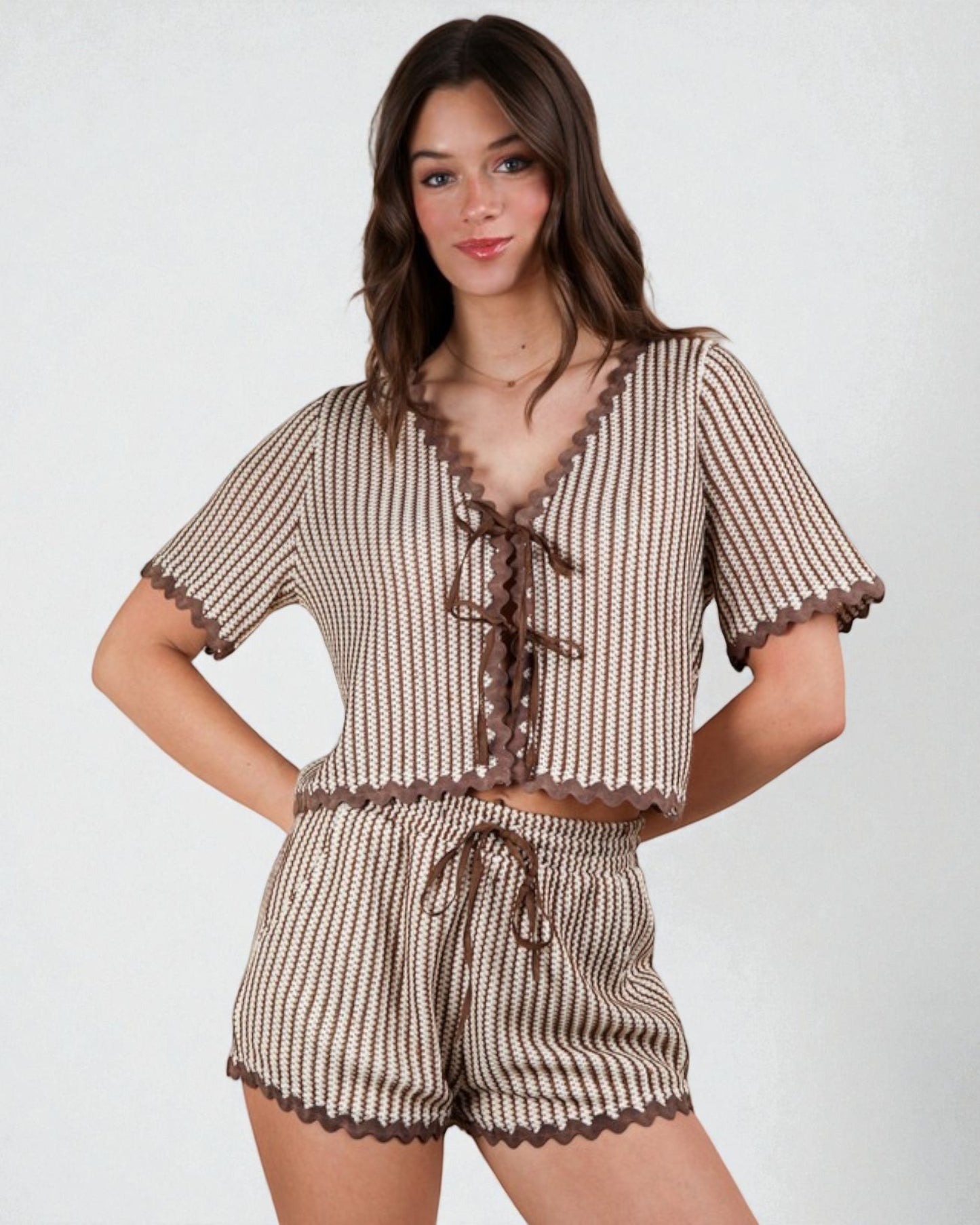 Woman wearing a brown and white striped outfit with lace details on a white background
