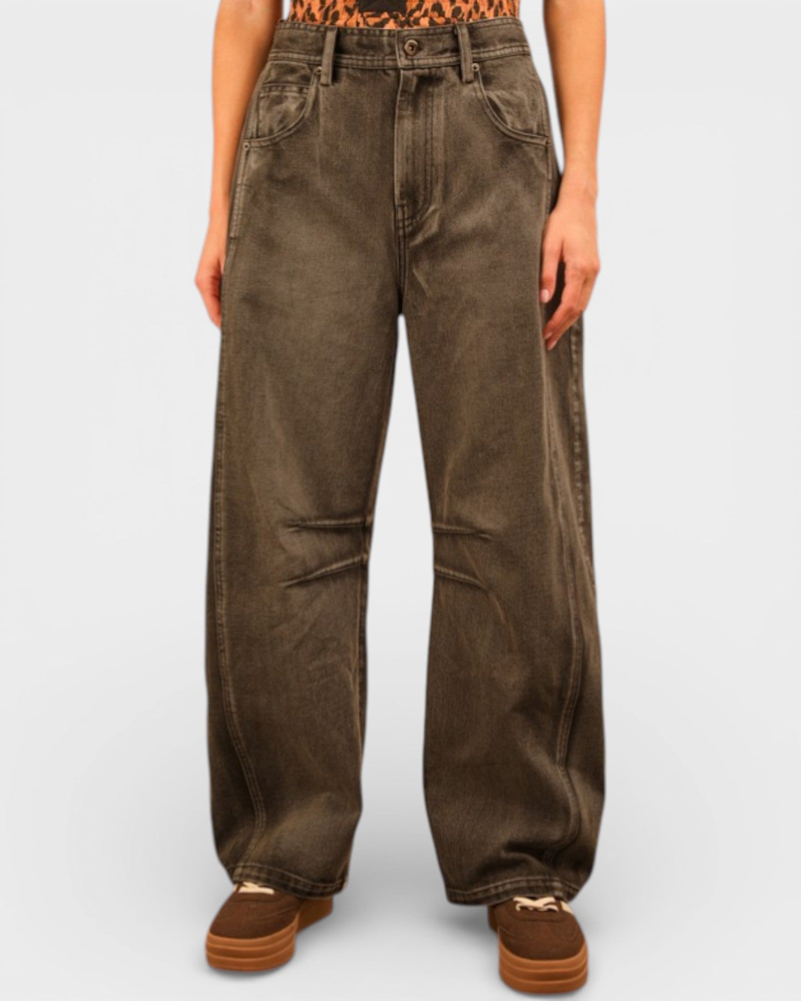 Brown wide-leg jeans worn by a person on a white background