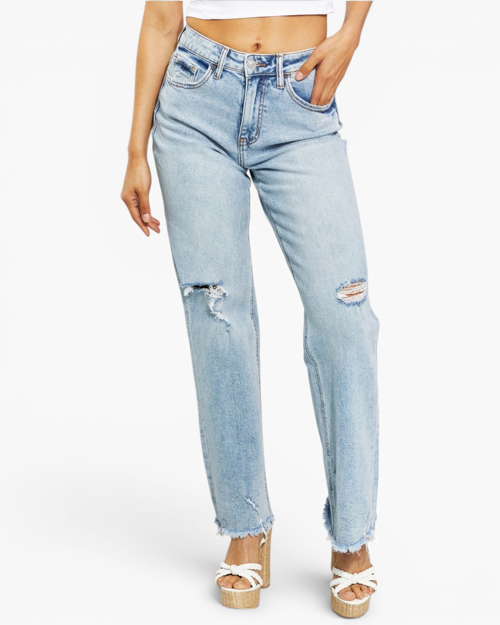 Light wash blue distressed jeans with frayed hems and ripped details on the thighs, shown on a model wearing white platform sandals against a plain white background.