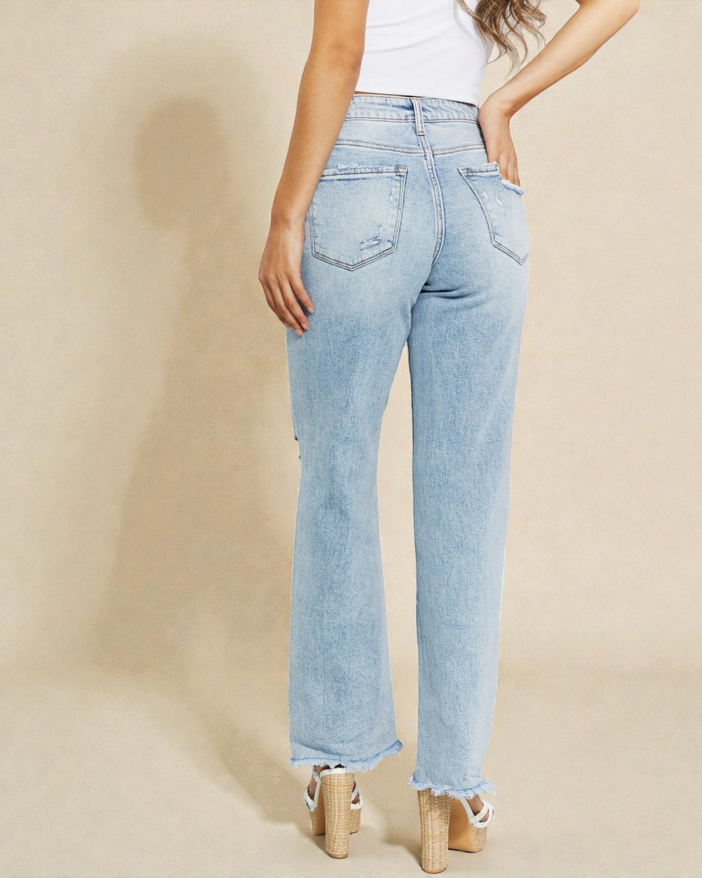 Light blue jeans worn by a person on a beige background