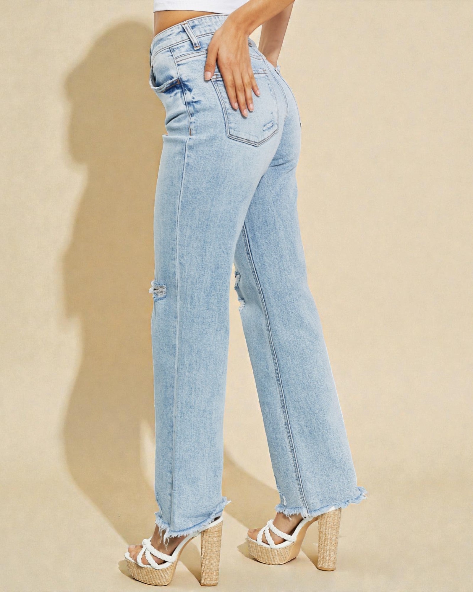 Light blue jeans worn by a person on a beige background