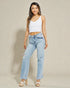 Woman wearing light blue jeans and a white top against a beige background