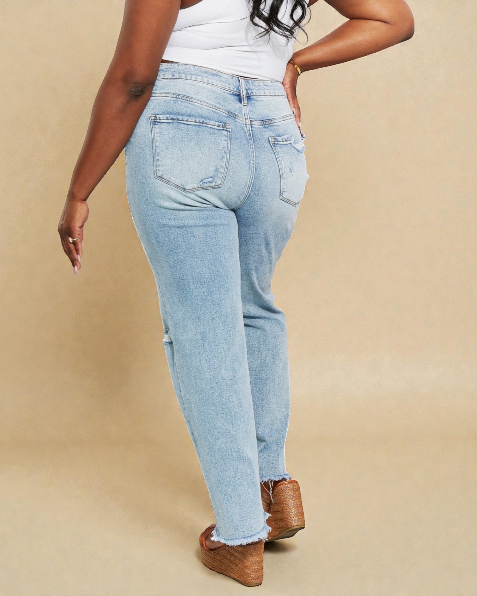 Person wearing light blue jeans and brown shoes on a beige background