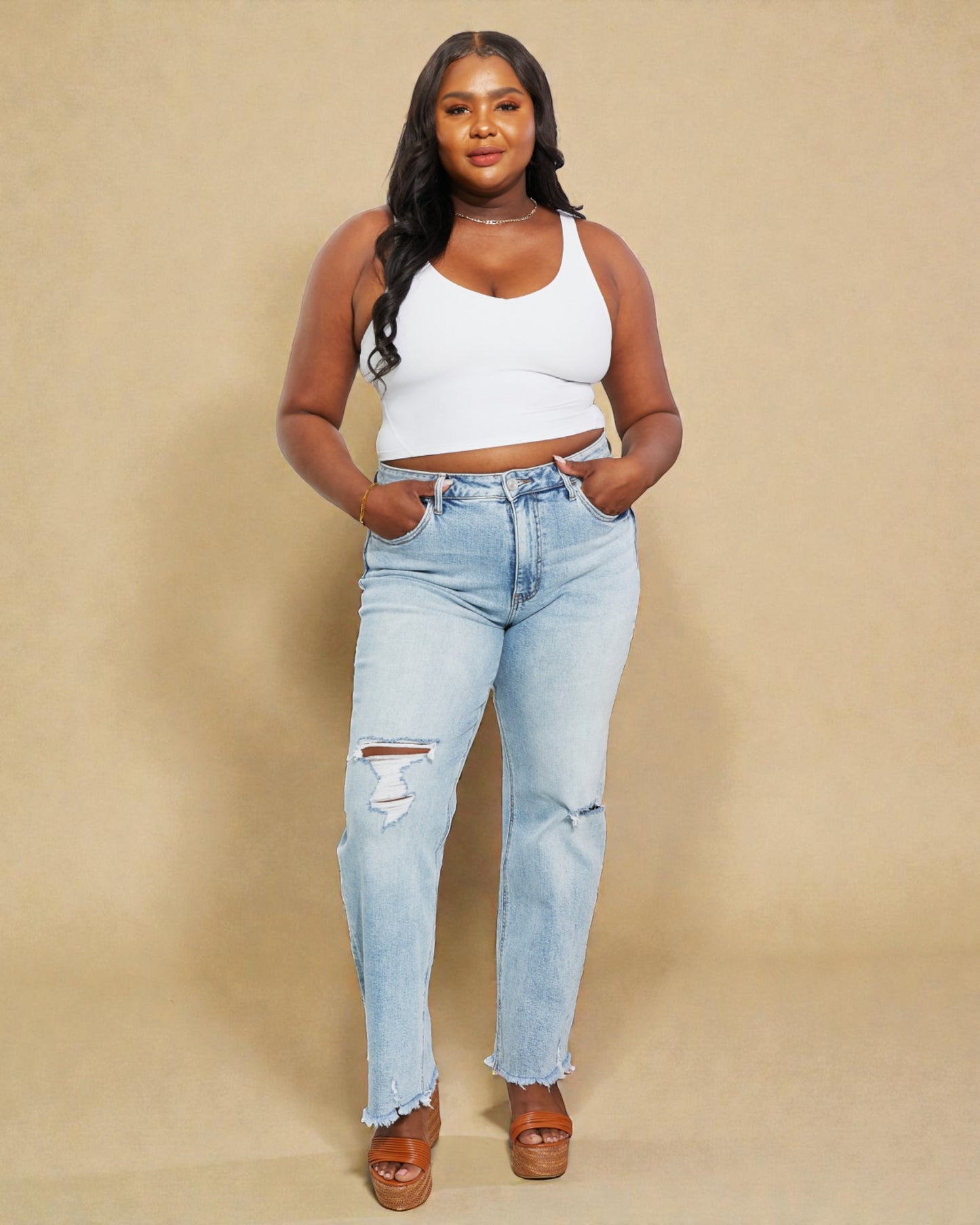 Woman wearing light blue jeans and a white top against a beige background
