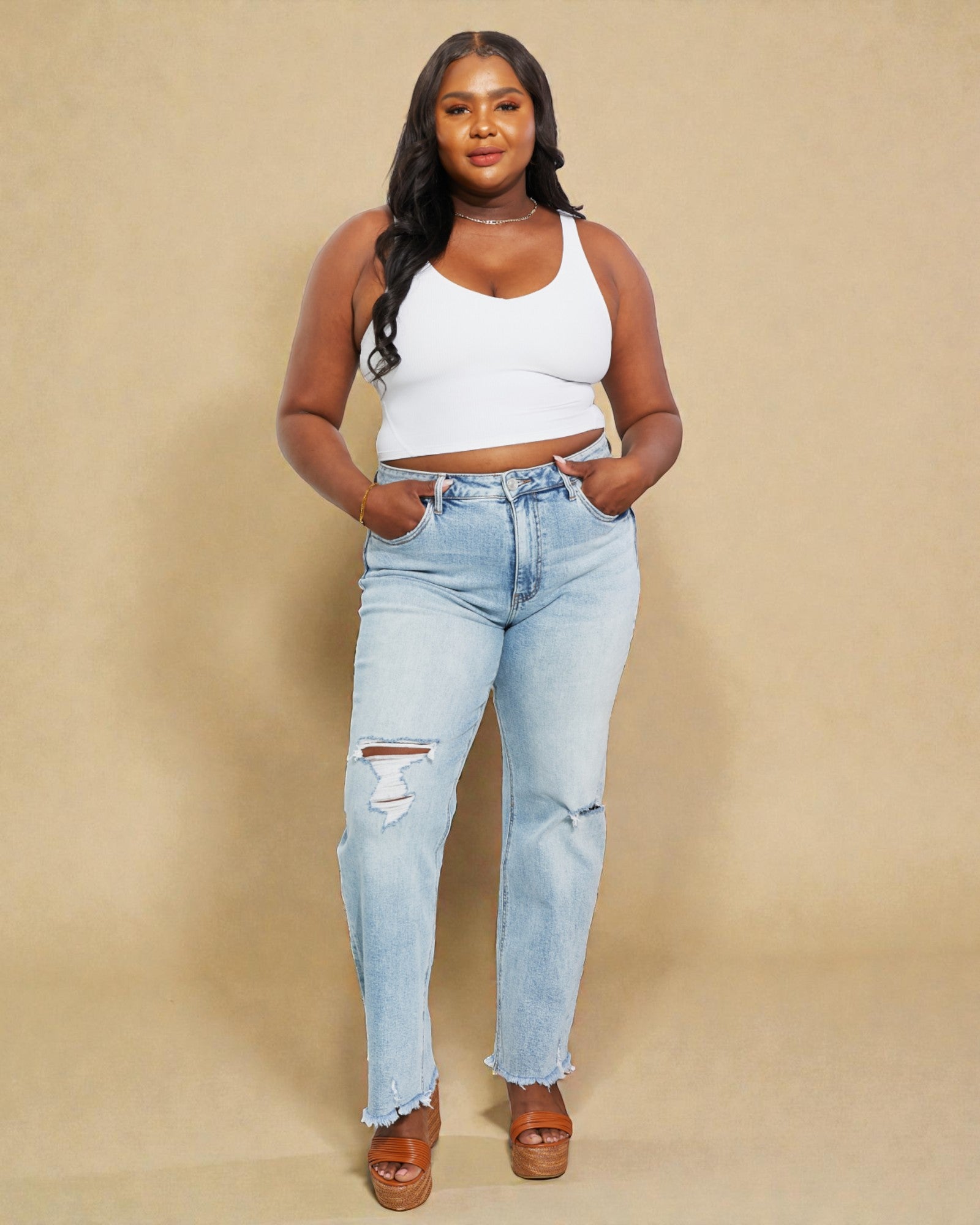 Woman wearing light blue jeans and a white top against a beige background